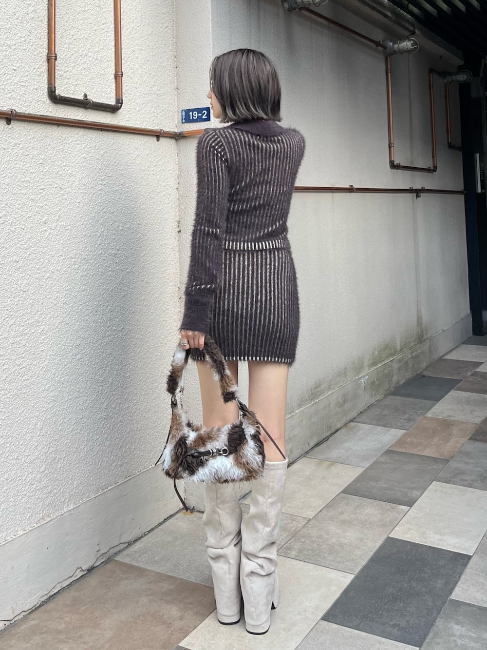 ブラウン系のニット/セーター、ブラウン系のスカート、ブラウン系のショルダーバッグを着用したレディースの秋コーディネートの3枚目の写真