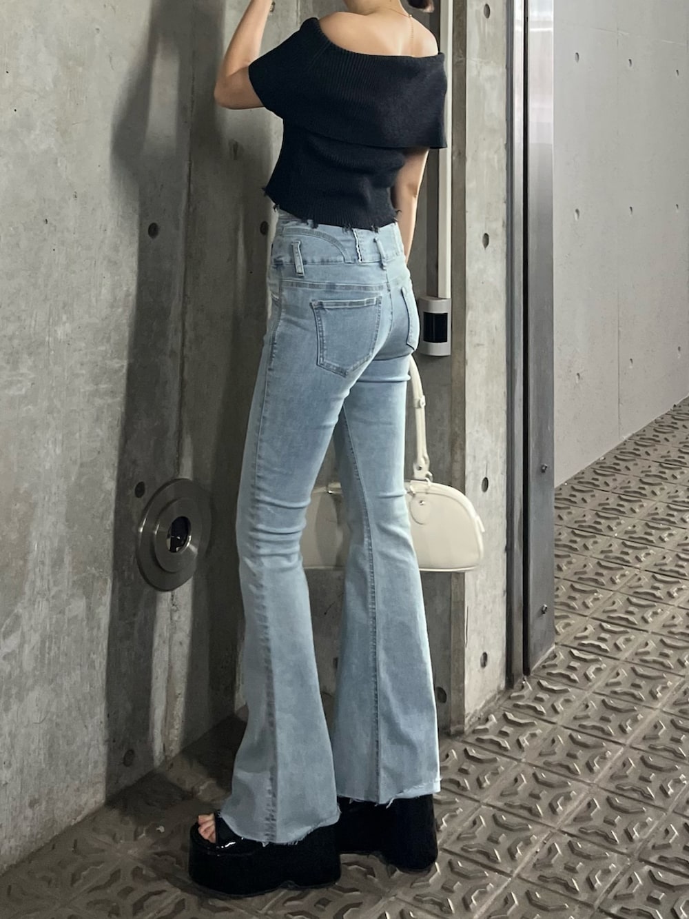 ブラック系のニット/セーター、ブルー系のデニムパンツ、ブラック系のサンダルを着用したレディースの春コーディネートの2枚目の写真
