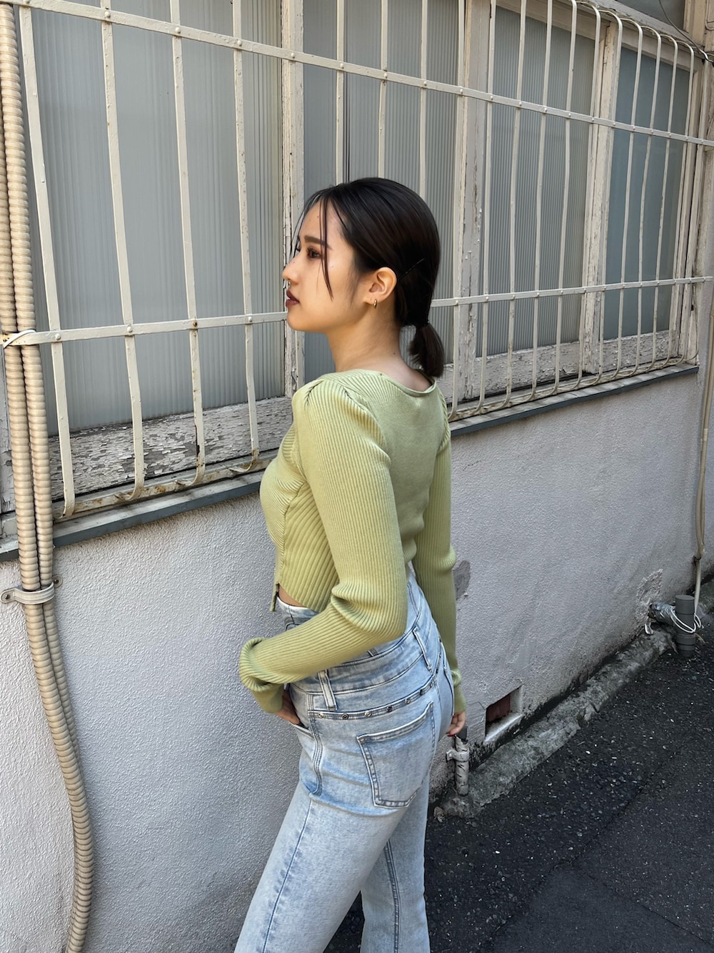 ブルー系のデニムパンツ、ホワイト系のスニーカー、イエロー系のニット/セーターを着用したレディースの春コーディネートの5枚目の写真