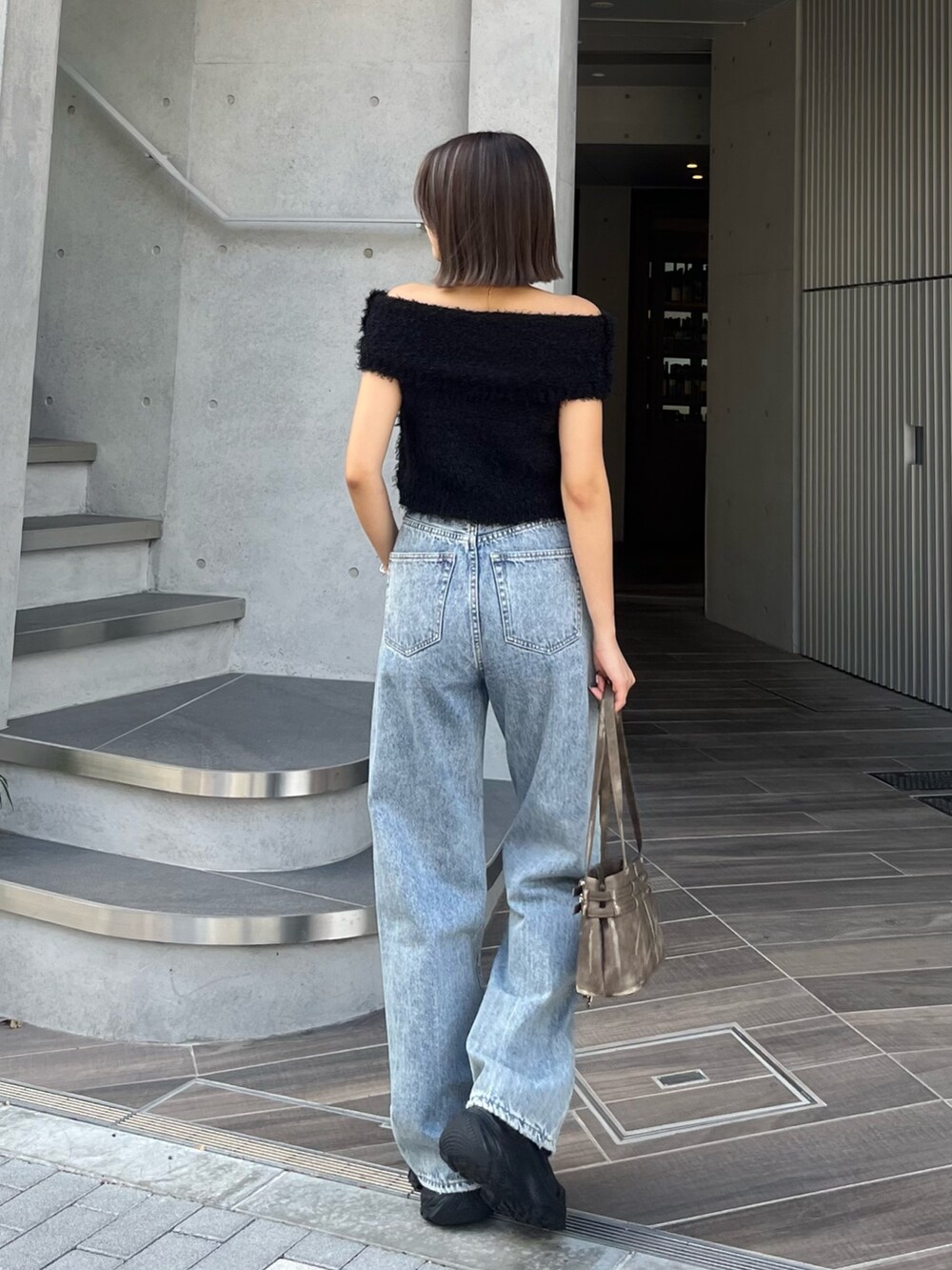 ブラウン系のハンドバッグ、ブラック系のスニーカー、ブルー系のデニムパンツを着用したレディースの夏コーディネートの3枚目の写真