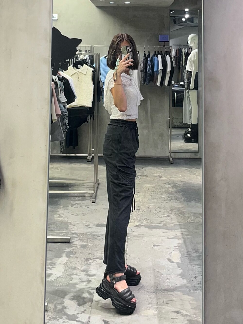 グレー系のサンダル、ブラック系のスカート、ホワイト系のキャミソールを着用したレディースの夏コーディネートの2枚目の写真