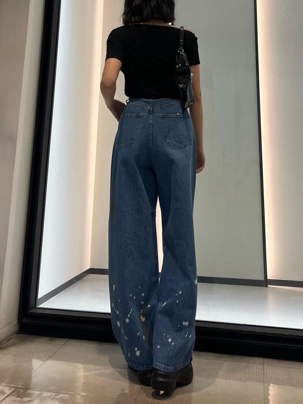 ブラック系のショルダーバッグ、ブルー系のデニムパンツ、ブラック系のサンダルを着用したレディースの春コーディネートの3枚目の写真