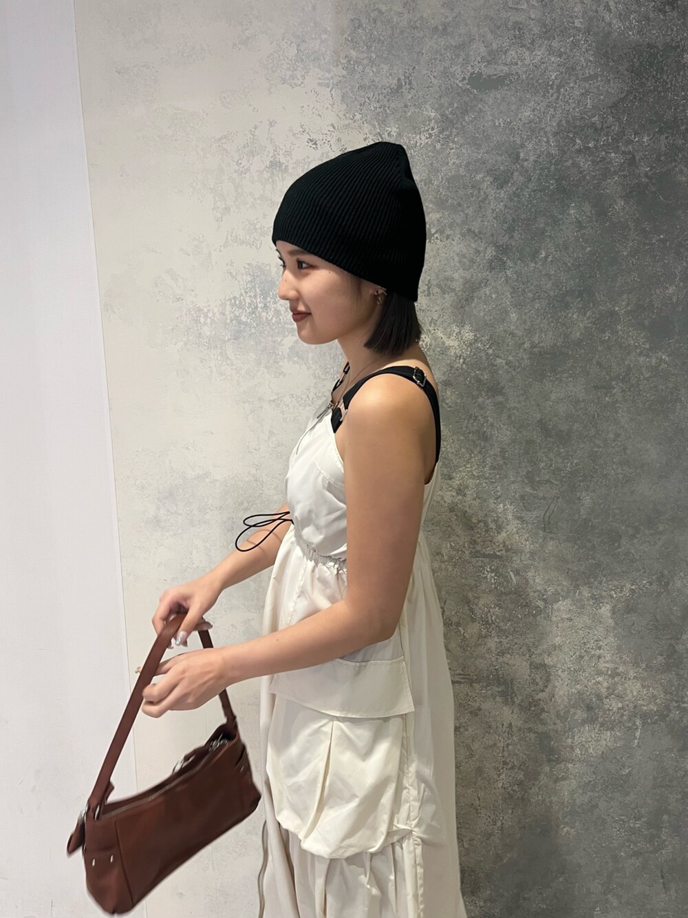 ブラウン系のハンドバッグ、ホワイト系のワンピース、ブラック系のサンダルを着用したレディースの春コーディネートの2枚目の写真