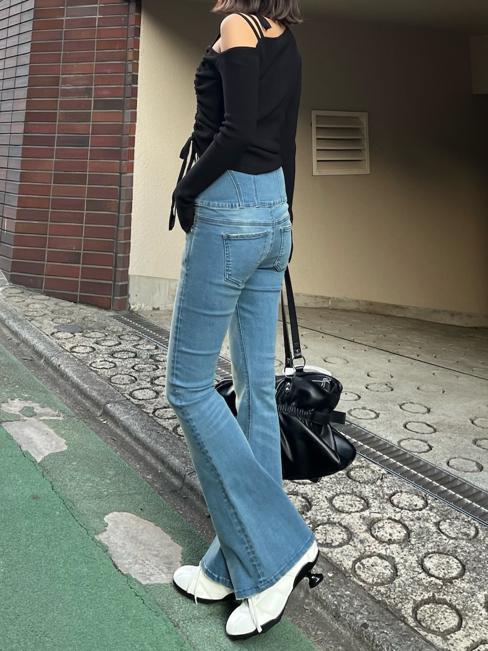 ブラック系のトートバッグ、ブラック系のニット/セーター、ブルー系のデニムパンツを着用したレディースの冬コーディネートの2枚目の写真