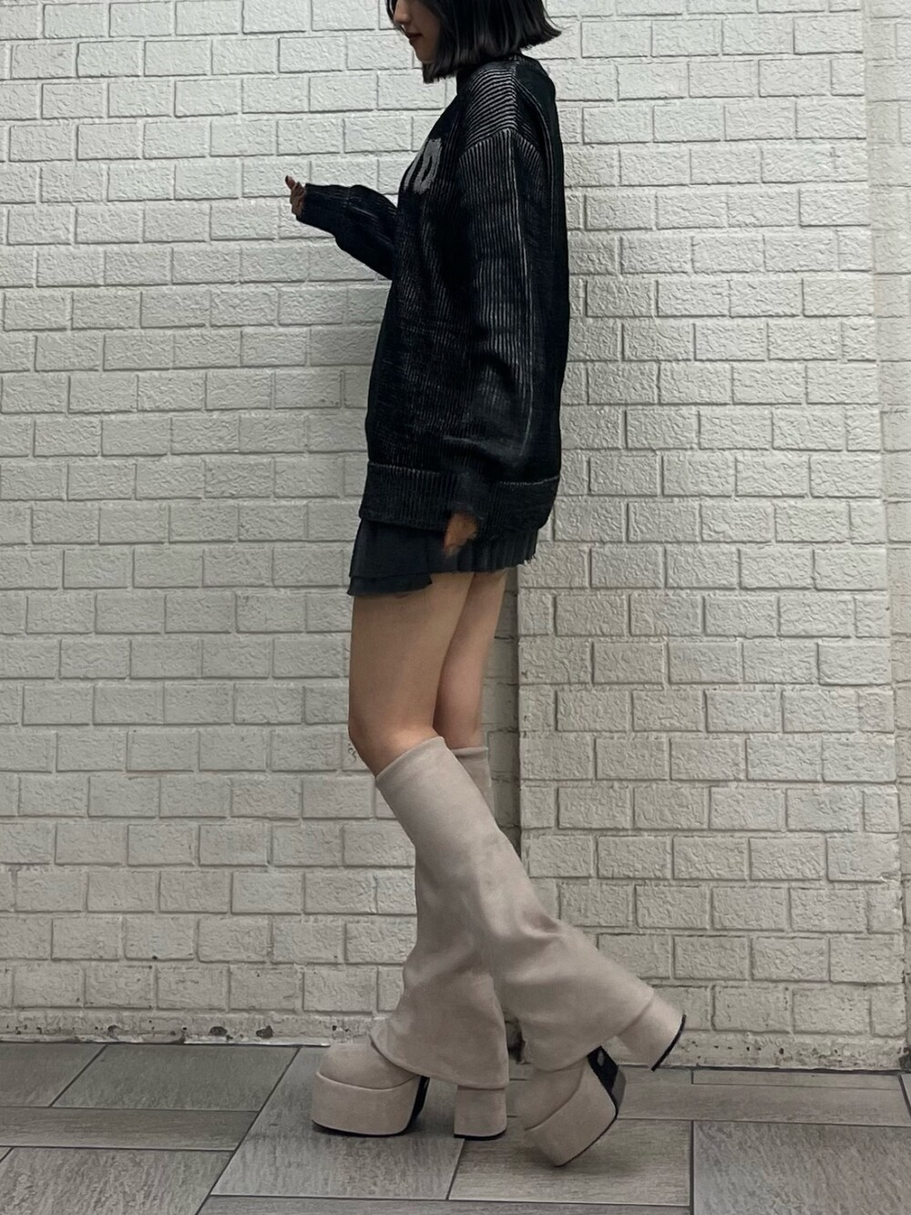 ブラック系のニット/セーター、グレー系のスカート、ホワイト系のブーツを着用したレディースの秋コーディネートの2枚目の写真