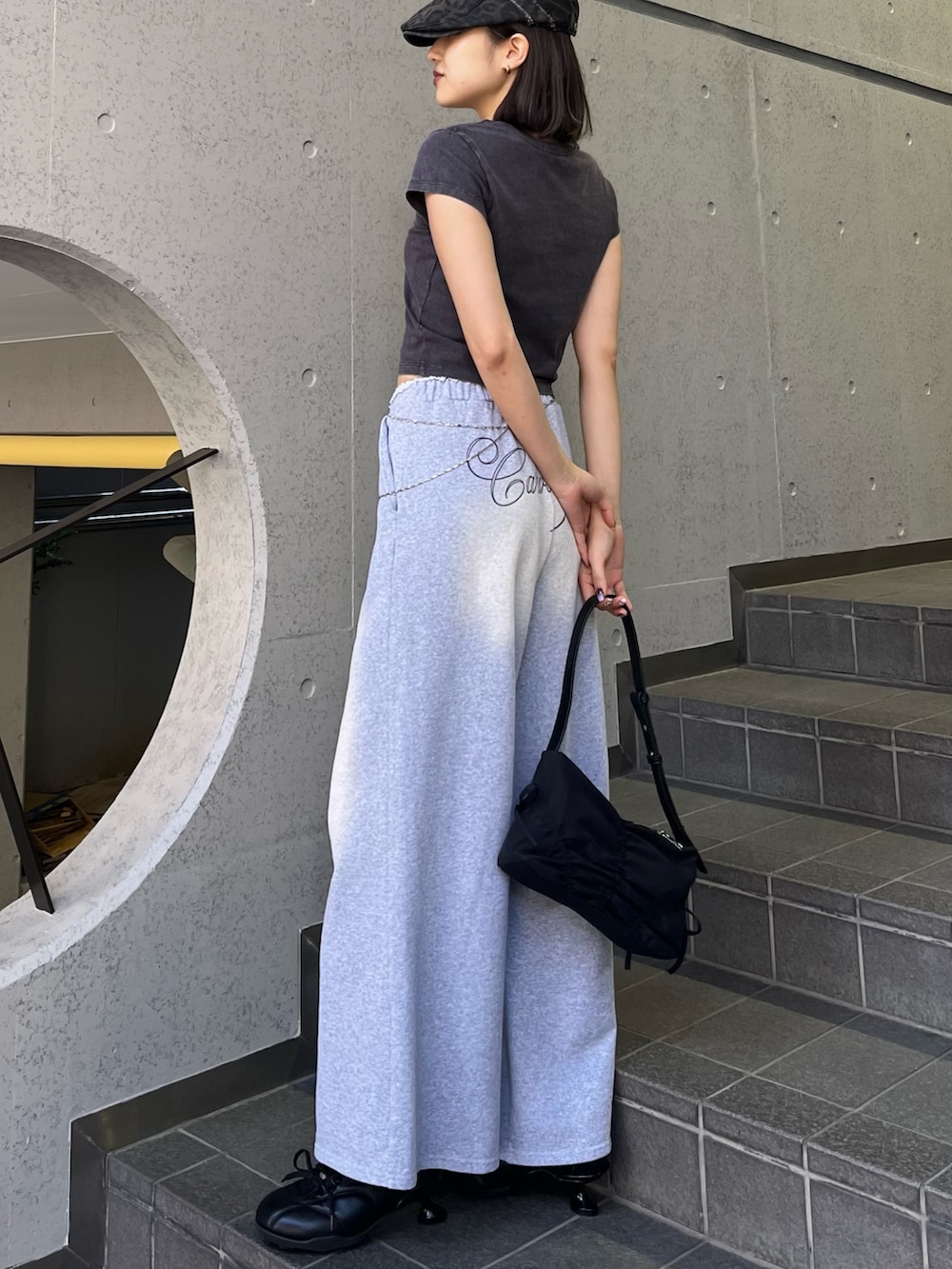 ブラック系のTシャツ/カットソー、ブラック系のスニーカー、グレー系のスウェットパンツを着用したレディースの春コーディネートの2枚目の写真