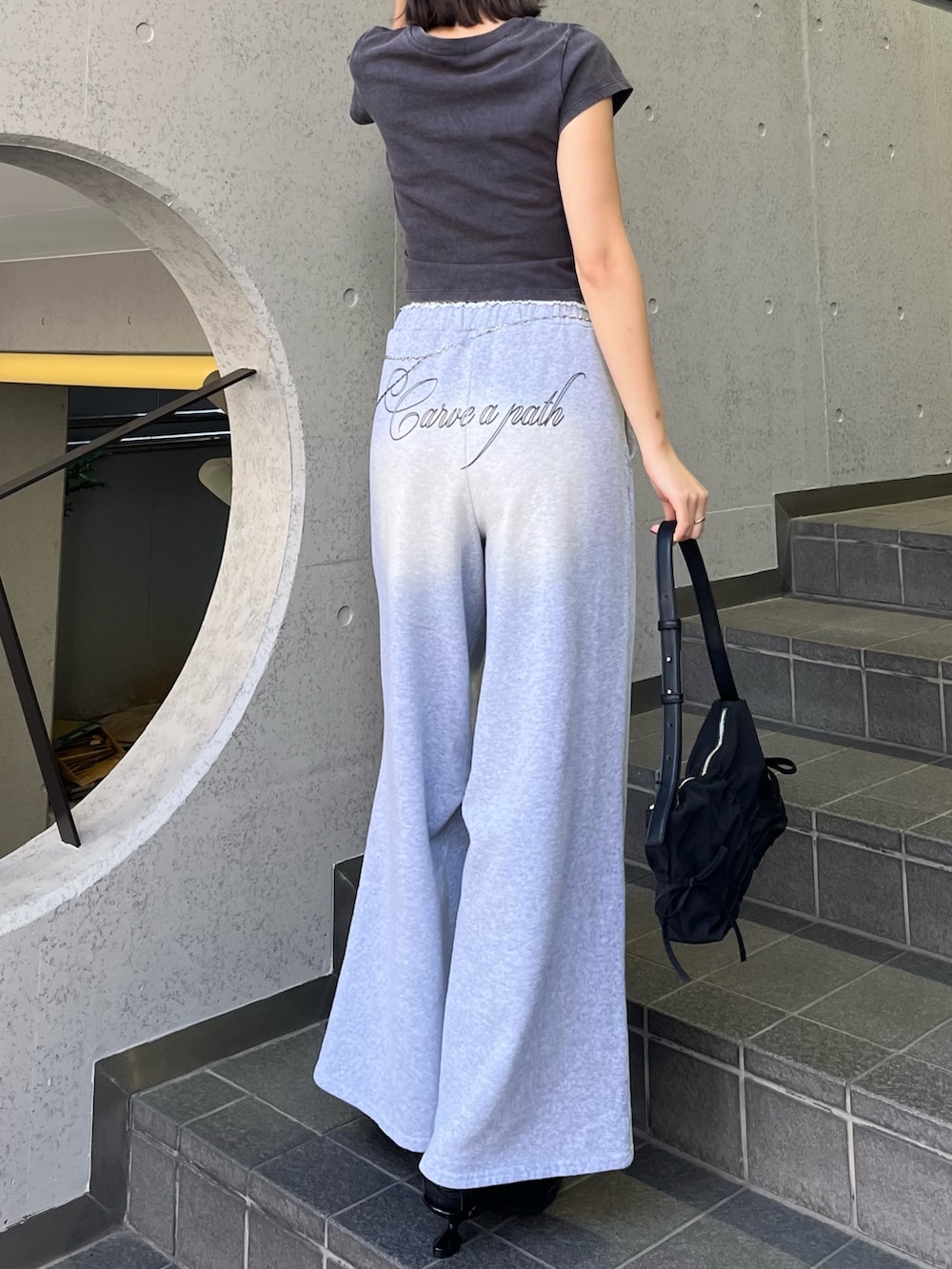 ブラック系のTシャツ/カットソー、ブラック系のスニーカー、グレー系のスウェットパンツを着用したレディースの春コーディネートの3枚目の写真