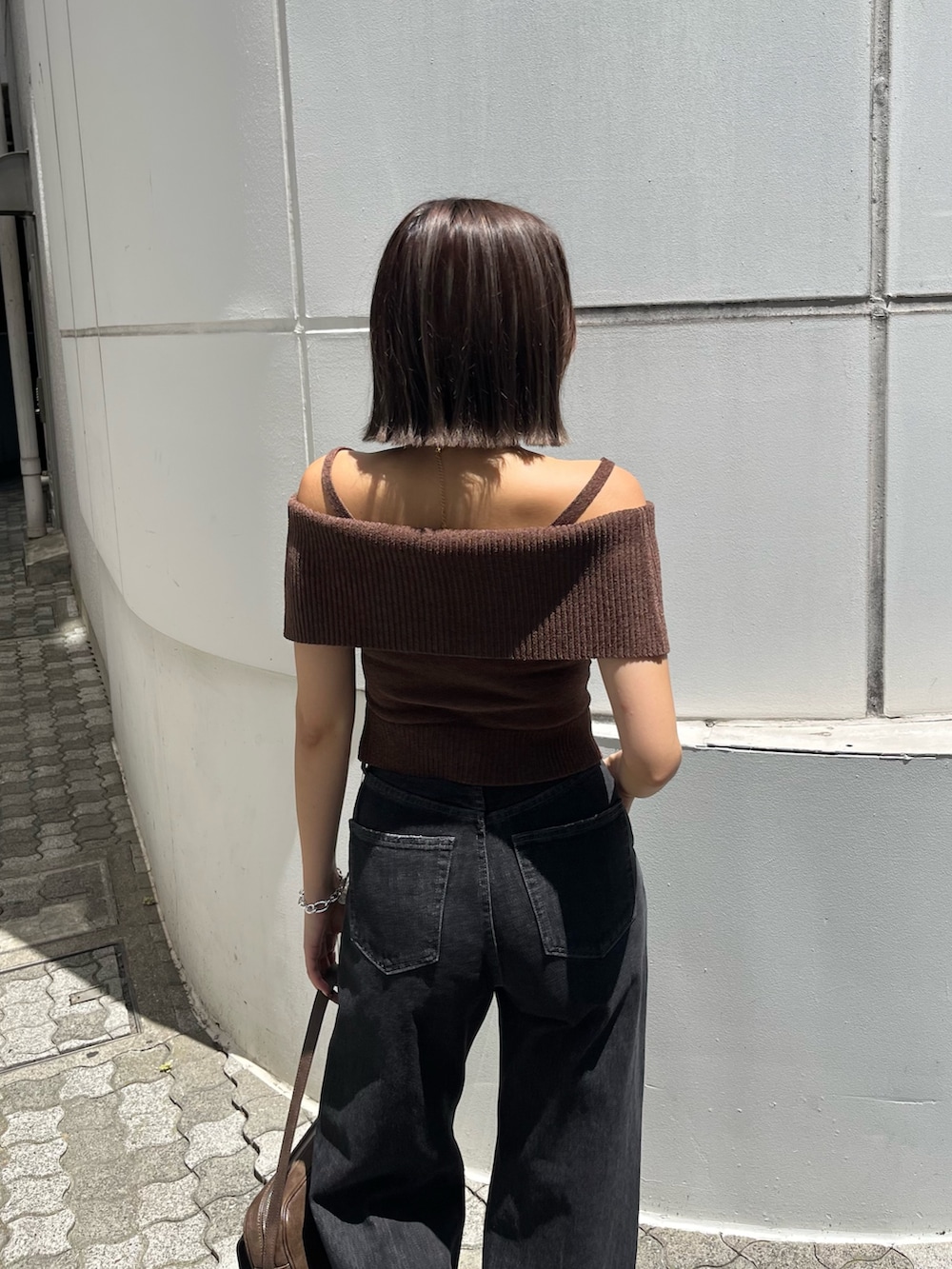 ブラウン系のニット/セーター、ブラウン系のハンドバッグ、ブラック系のスニーカーを着用したレディースの夏コーディネートの3枚目の写真