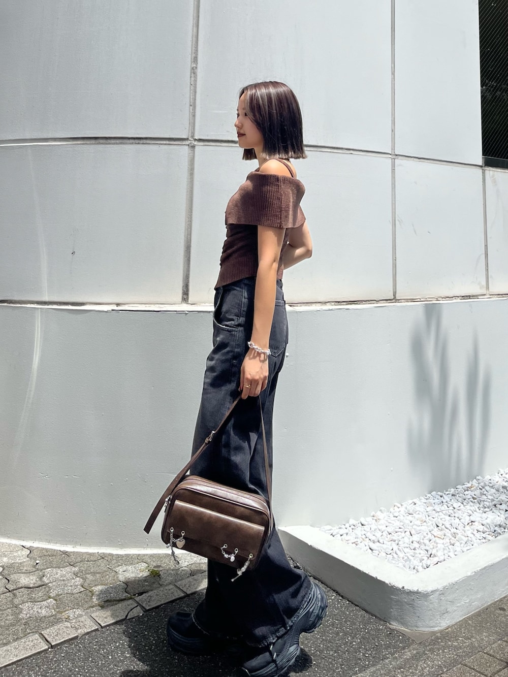 ブラウン系のニット/セーター、ブラウン系のハンドバッグ、ブラック系のスニーカーを着用したレディースの夏コーディネートの2枚目の写真