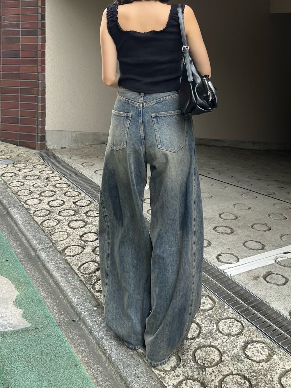 ブラック系のタンクトップ、ブルー系のデニムパンツを着用したレディースの夏コーディネートの2枚目の写真