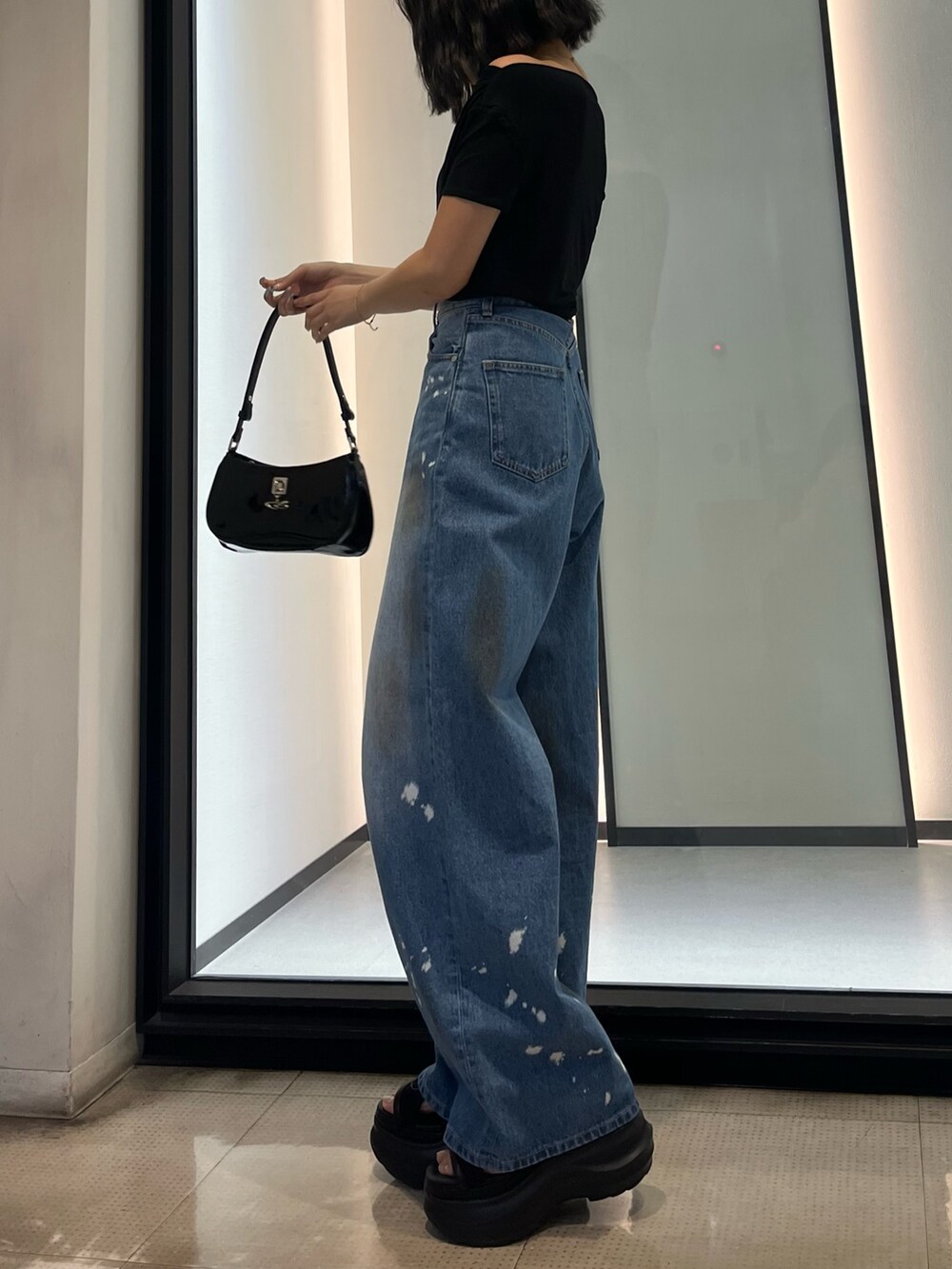 ブラック系のショルダーバッグ、ブルー系のデニムパンツ、ブラック系のサンダルを着用したレディースの春コーディネートの2枚目の写真