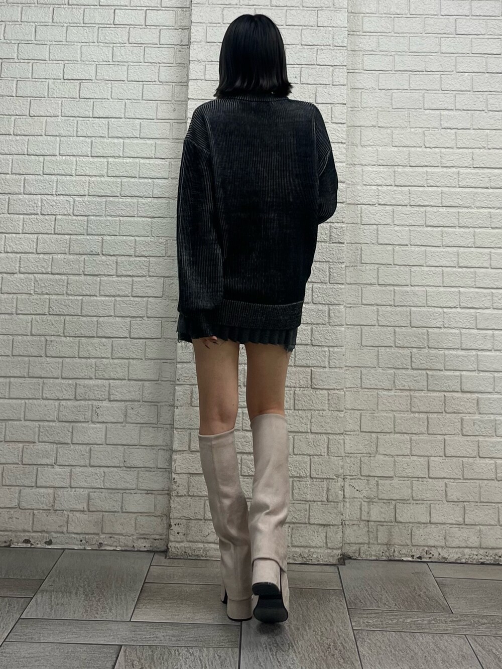 ブラック系のニット/セーター、グレー系のスカート、ホワイト系のブーツを着用したレディースの秋コーディネートの3枚目の写真