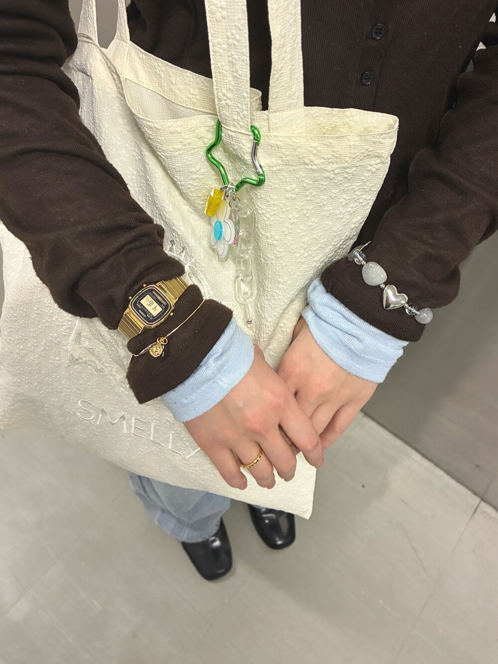 ホワイト系のトートバッグ、ゴールド系のブレスレット、ゴールド系のリングを着用したレディースの冬コーディネートの3枚目の写真