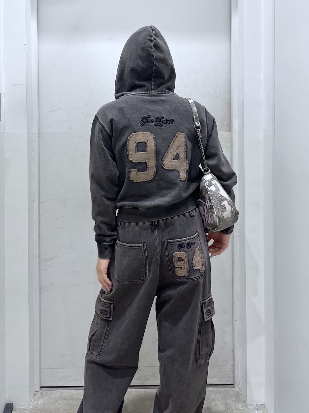 ブラック系のパーカー、ブラック系のスウェットパンツ、ベージュ系のトレンチコートを着用したレディースの冬コーディネートの4枚目の写真