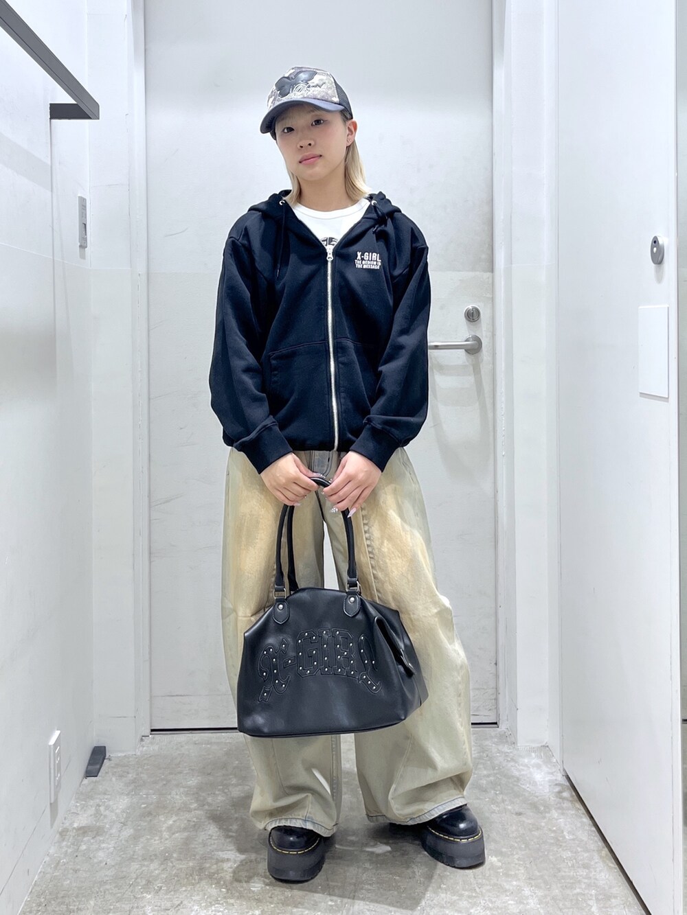 ブラック系のパーカー、ブルー系のデニムパンツ、ブラック系のショルダーバッグを着用したレディースの冬コーディネートの2枚目の写真