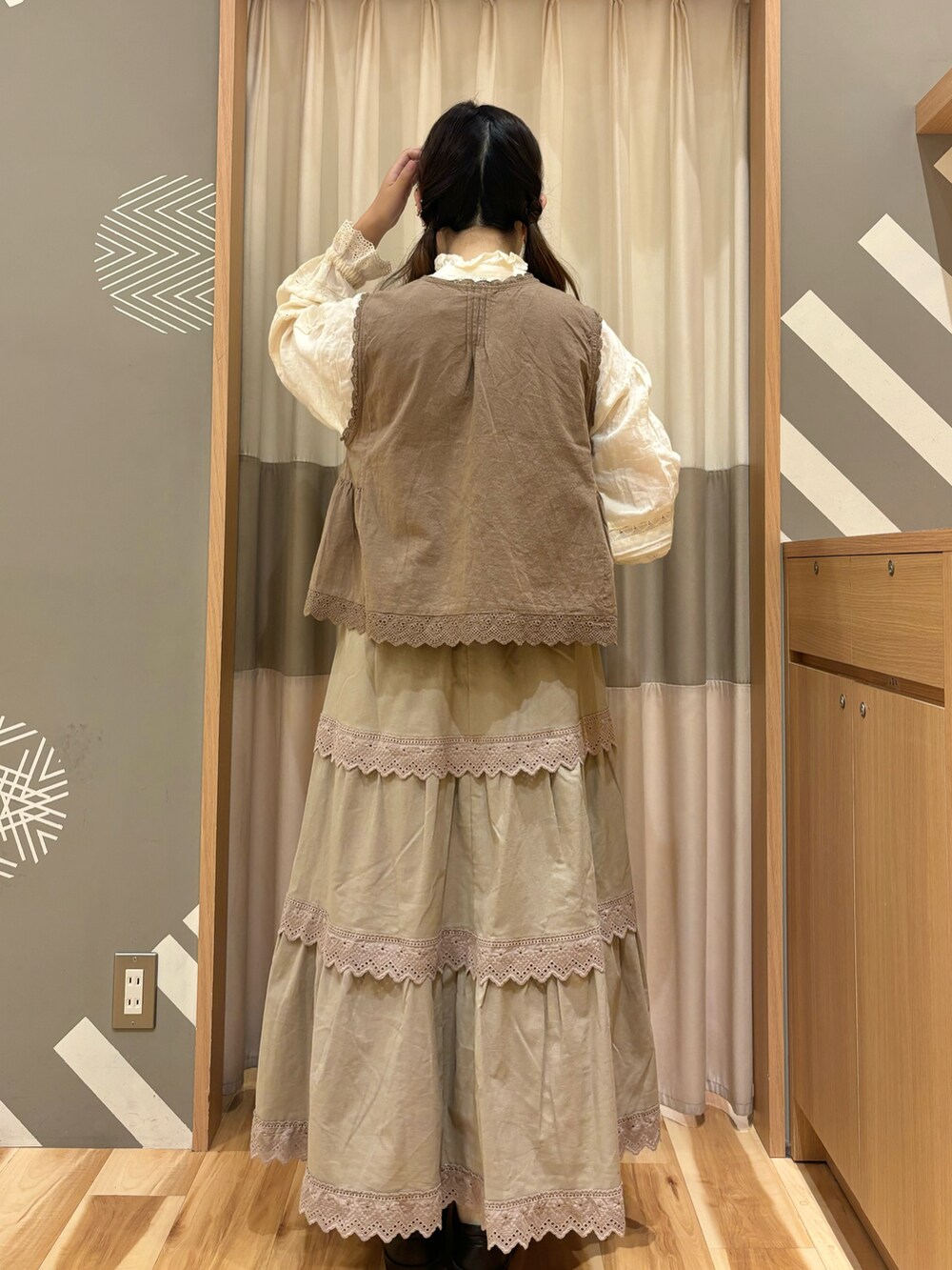 ブラウン系のスカート、ブラウン系のベスト、ホワイト系のシャツ/ブラウスを着用したレディースの秋コーディネートの3枚目の写真