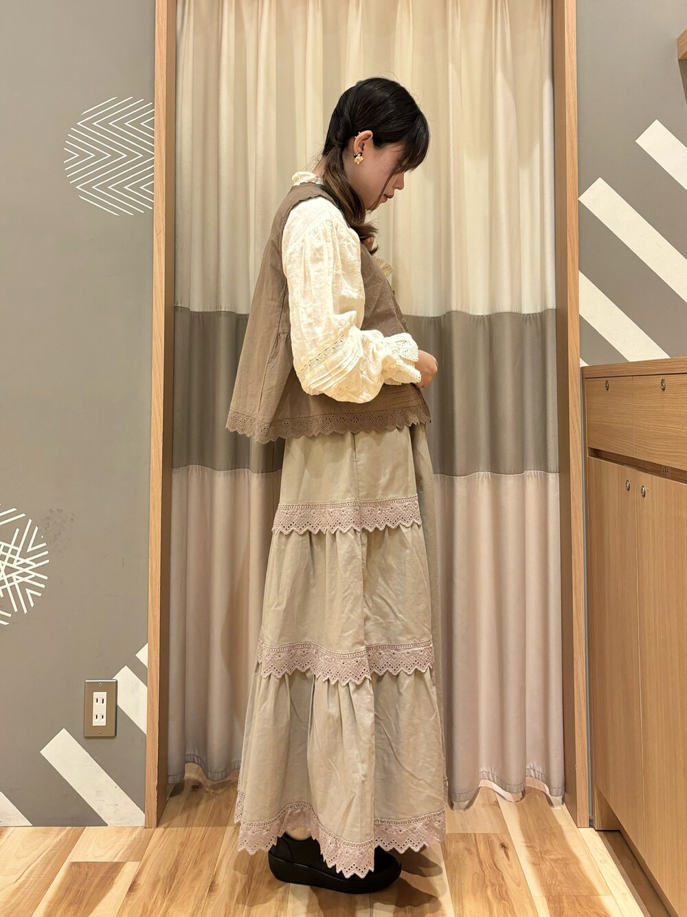 ブラウン系のスカート、ブラウン系のベスト、ホワイト系のシャツ/ブラウスを着用したレディースの秋コーディネートの2枚目の写真