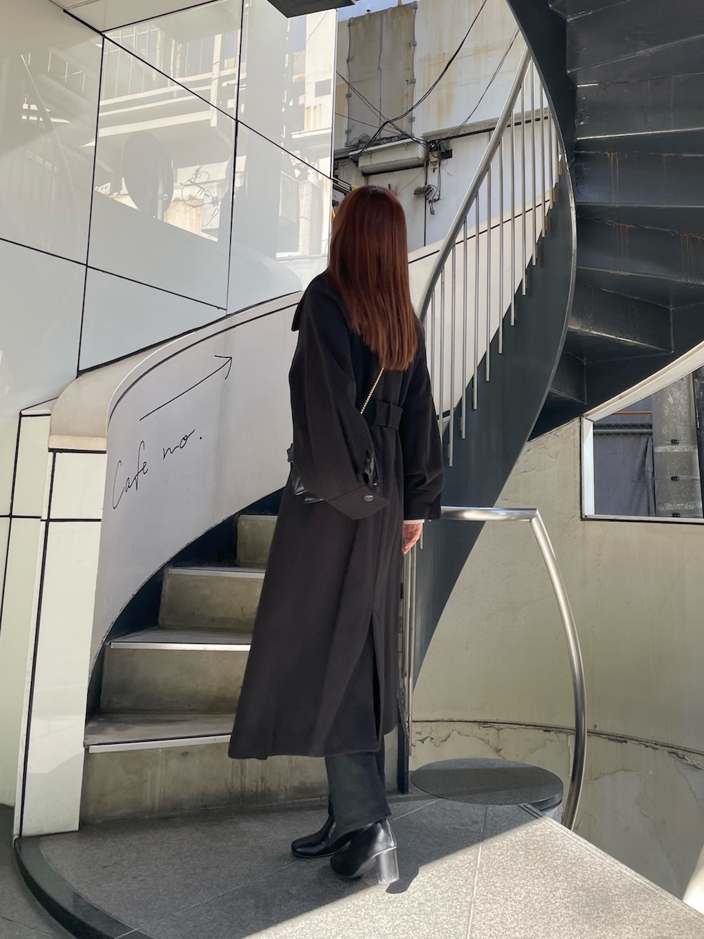 ブラック系のステンカラーコート、ホワイト系のニット/セーター、ブラック系のデニムパンツを着用したレディースの秋コーディネートの3枚目の写真