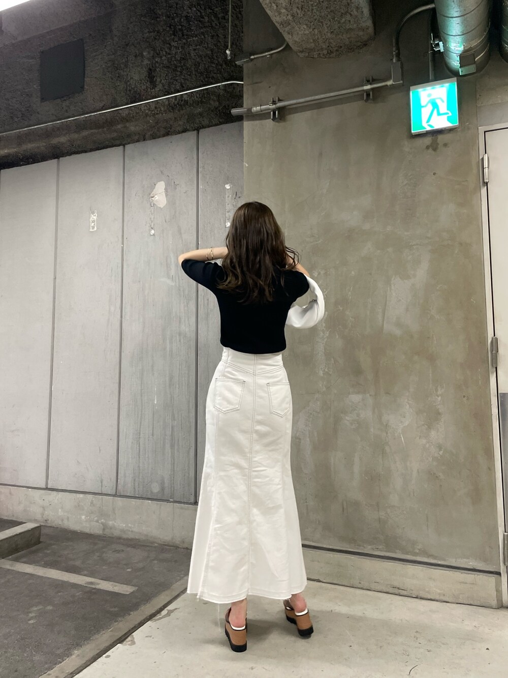 ブラック系のニット/セーター、ホワイト系のデニムスカート、ホワイト系のハンドバッグを着用したレディースの春コーディネートの3枚目の写真