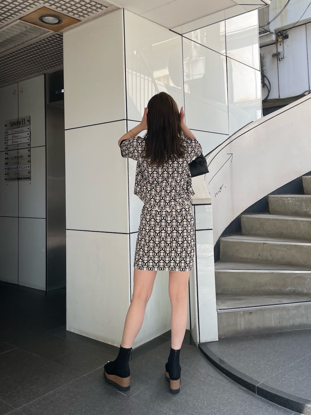 ブラック系のポロシャツ、ブラック系のスカート、ブラック系のブーツを着用したレディースの春コーディネートの4枚目の写真