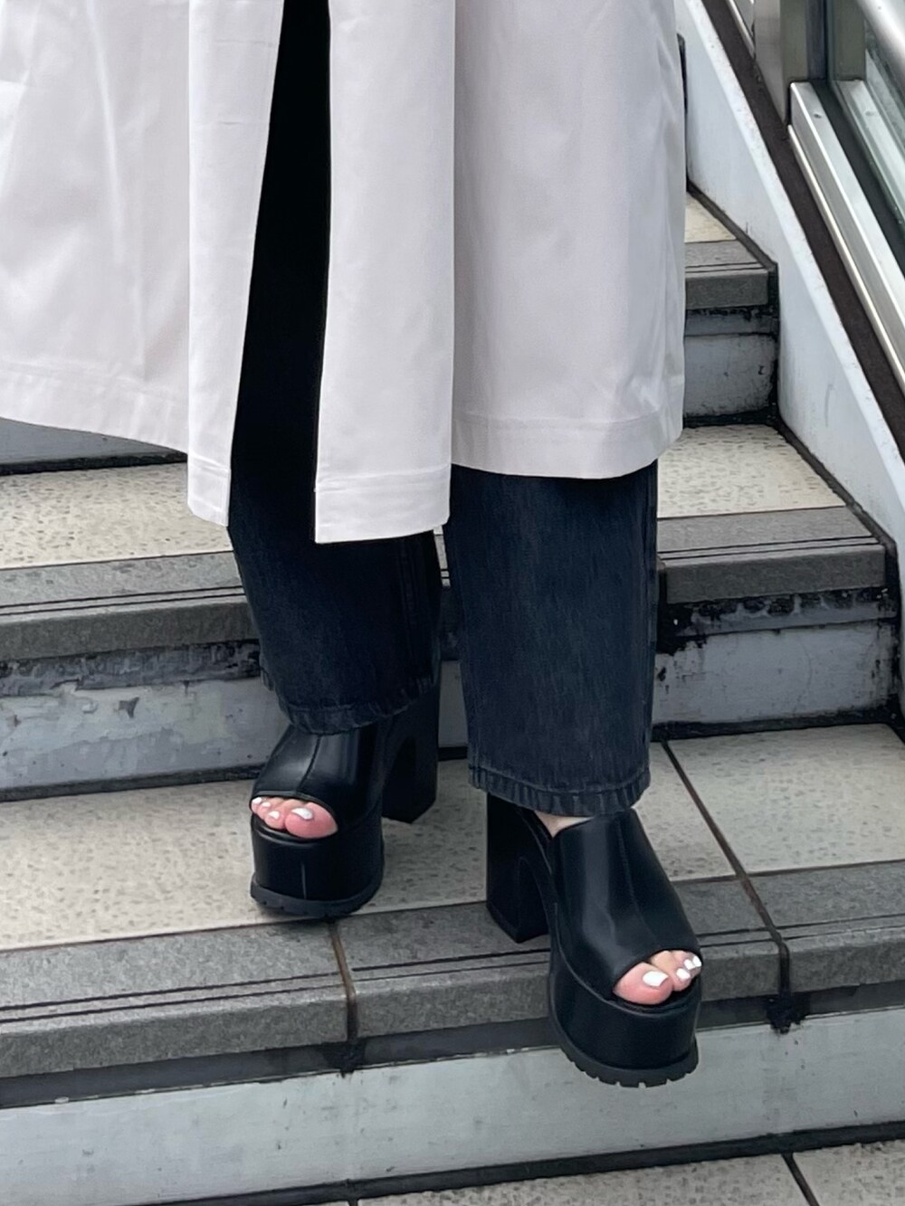 ホワイト系のトレンチコート、ブラック系のサンダル、ブラック系のデニムパンツを着用したレディースの春コーディネートの9枚目の写真