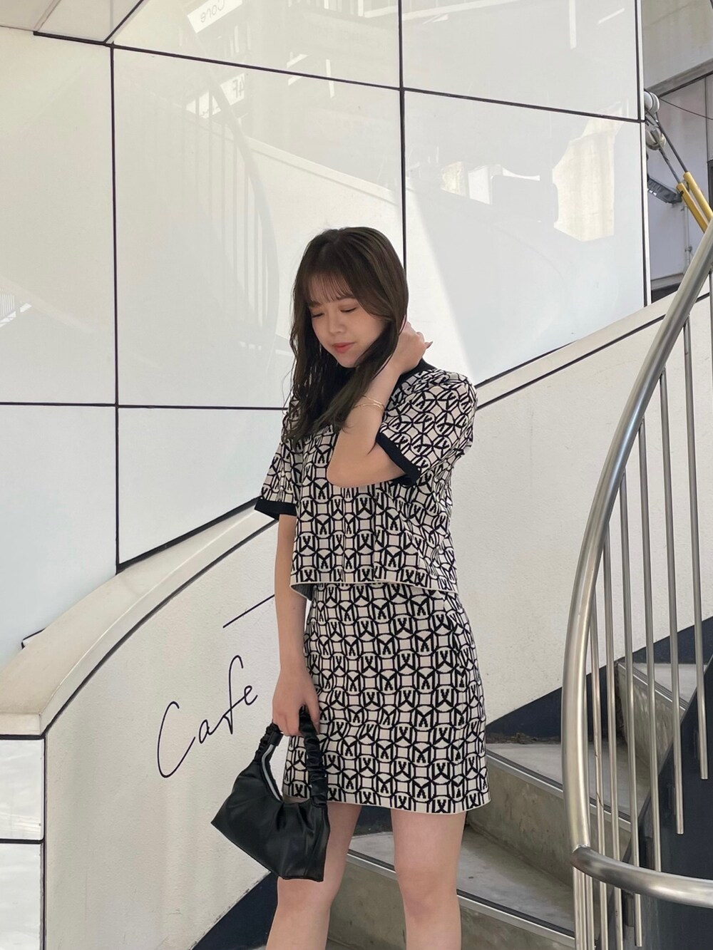 ブラック系のポロシャツ、ブラック系のスカート、ブラック系のブーツを着用したレディースの春コーディネートの5枚目の写真