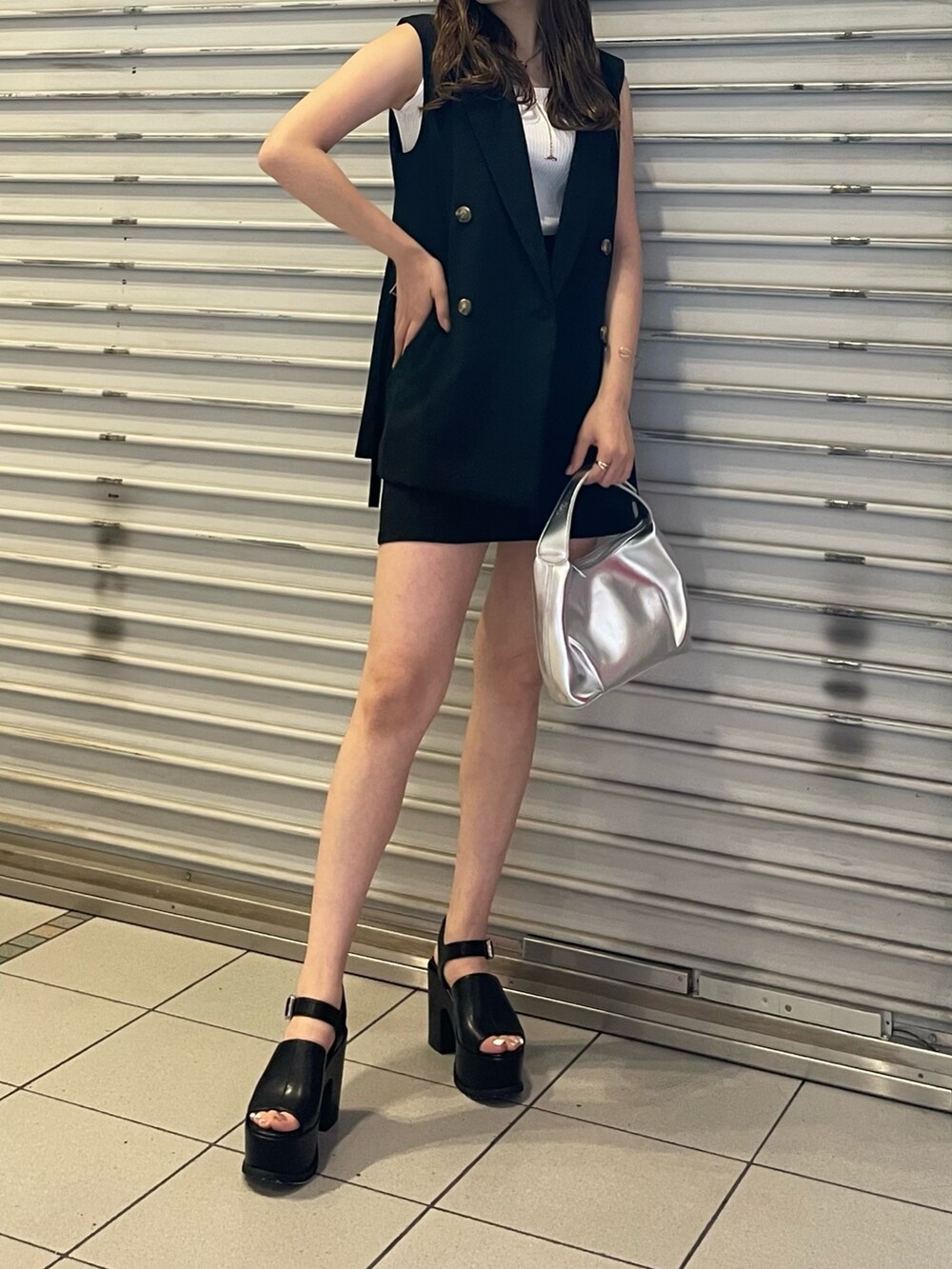 ブラック系のスカート、ホワイト系のタンクトップ、シルバー系のハンドバッグを着用したレディースの夏コーディネートの4枚目の写真