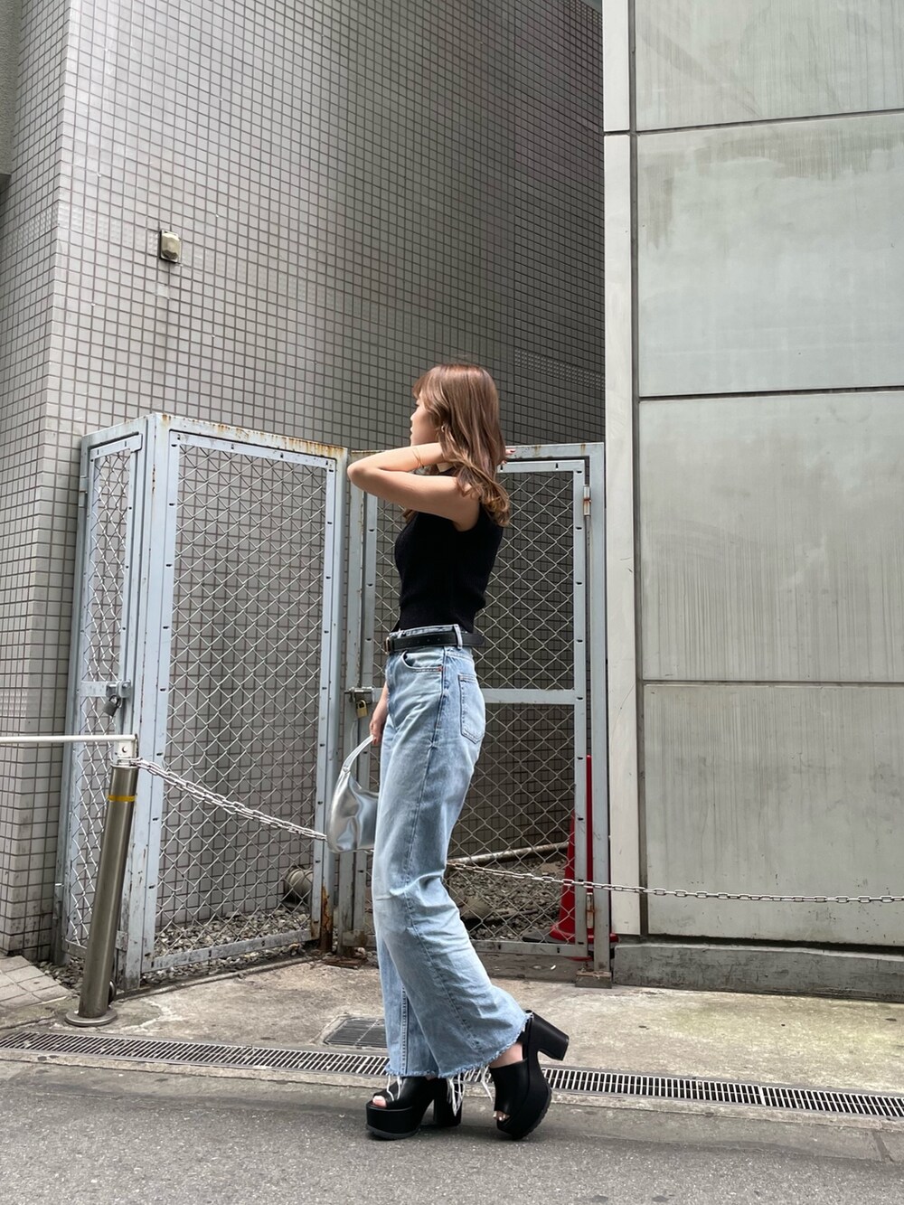 ブラック系のニット/セーター、シルバー系のハンドバッグ、ブラック系のサンダルを着用したレディースの春コーディネートの3枚目の写真