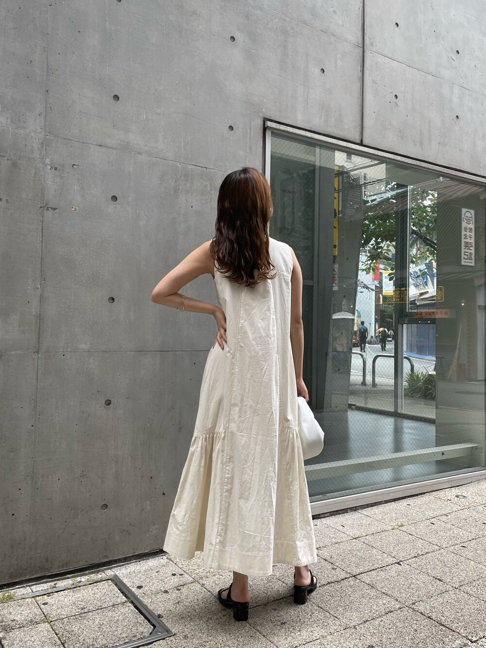 ホワイト系のワンピース、ホワイト系のハンドバッグ、ブラック系のサンダルを着用したレディースの夏コーディネートの4枚目の写真