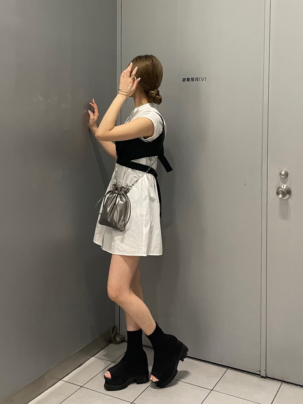 グレー系のショルダーバッグ、ブラック系のブーツ、ブラック系のワンピースを着用したレディースの春コーディネートの3枚目の写真