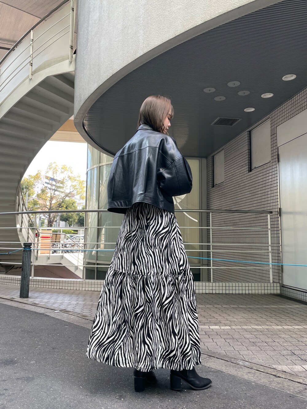 ブラック系のブルゾン、ホワイト系のスカート、ブラック系のニット/セーターを着用したレディースの春コーディネートの3枚目の写真