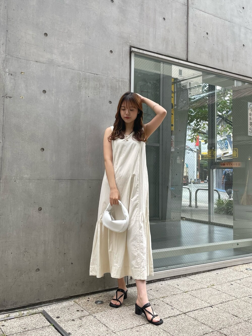 ホワイト系のワンピース、ホワイト系のハンドバッグ、ブラック系のサンダルを着用したレディースの夏コーディネートの2枚目の写真