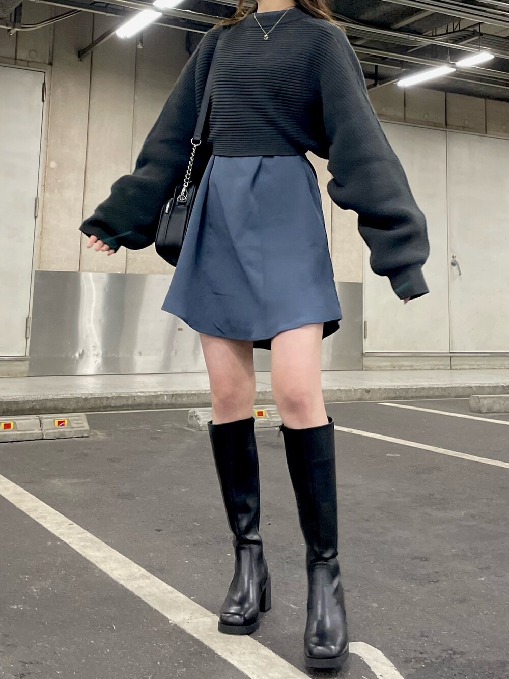 グレー系のワンピース、ブラック系のショルダーバッグ、ブラック系のブーツを着用したレディースの冬コーディネートの4枚目の写真