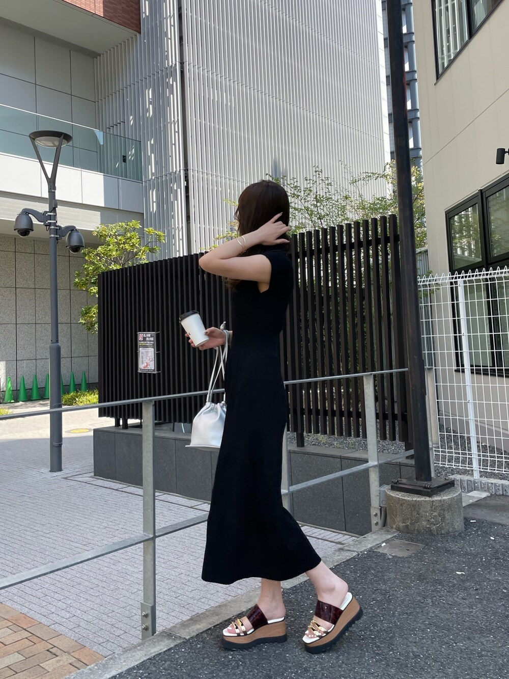 ブラック系のワンピース、シルバー系のハンドバッグ、その他のサンダルを着用したレディースの春コーディネートの2枚目の写真