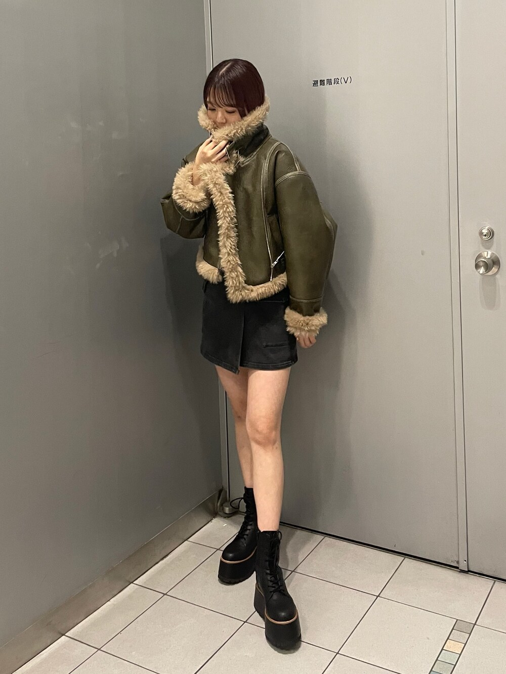 ブラック系のスカート、グリーン系のムートンコート、その他のTシャツ/カットソーを着用したレディースの夏コーディネートの2枚目の写真