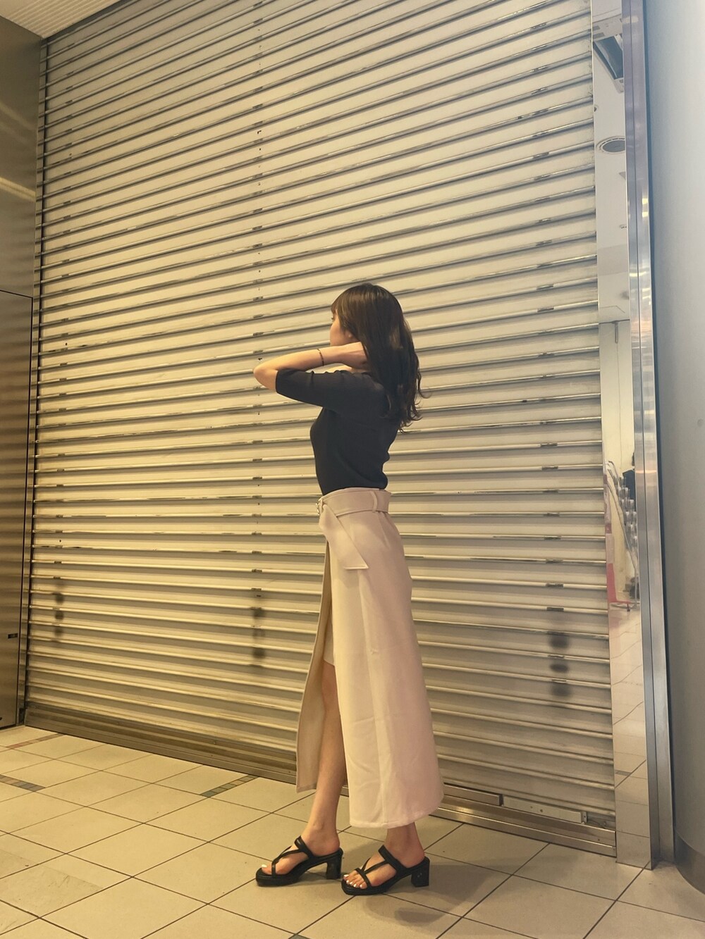 グレー系のニット/セーター、ホワイト系のスカート、ブラック系のサンダルを着用したレディースの春コーディネートの3枚目の写真