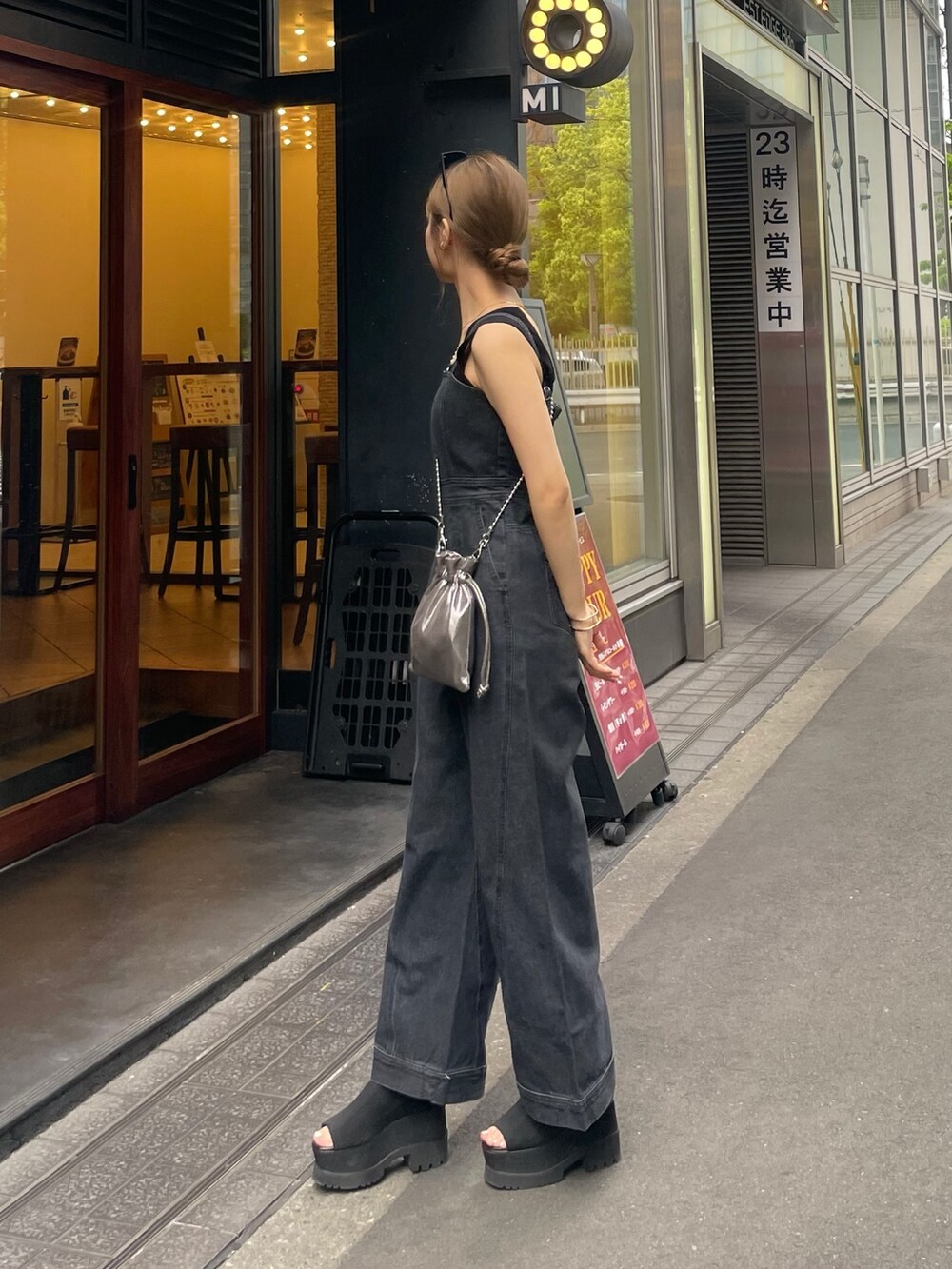 グレー系のショルダーバッグ、ブラック系のブーツ、ブラック系のニット/セーターを着用したレディースの春コーディネートの4枚目の写真