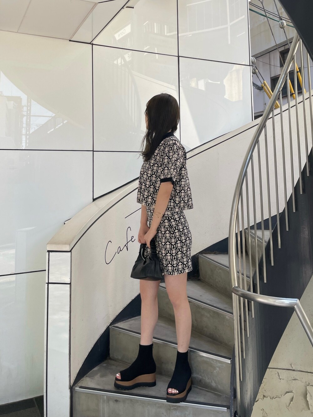 ブラック系のポロシャツ、ブラック系のスカート、ブラック系のブーツを着用したレディースの春コーディネートの3枚目の写真