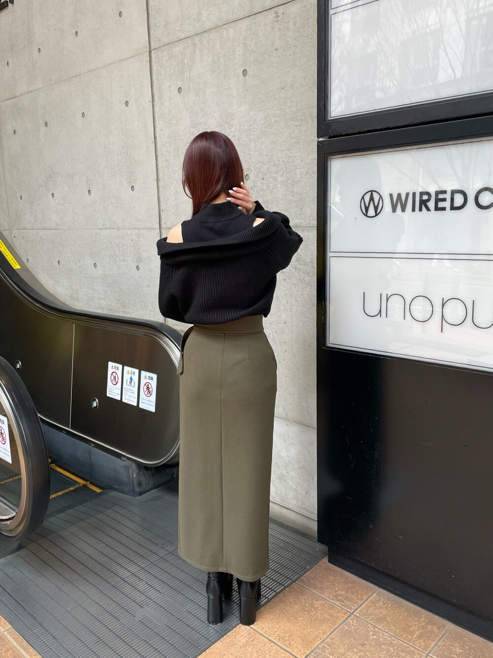 ブラック系のブーツ、グリーン系のスカート、ブラック系のニット/セーターを着用したレディースの冬コーディネートの4枚目の写真