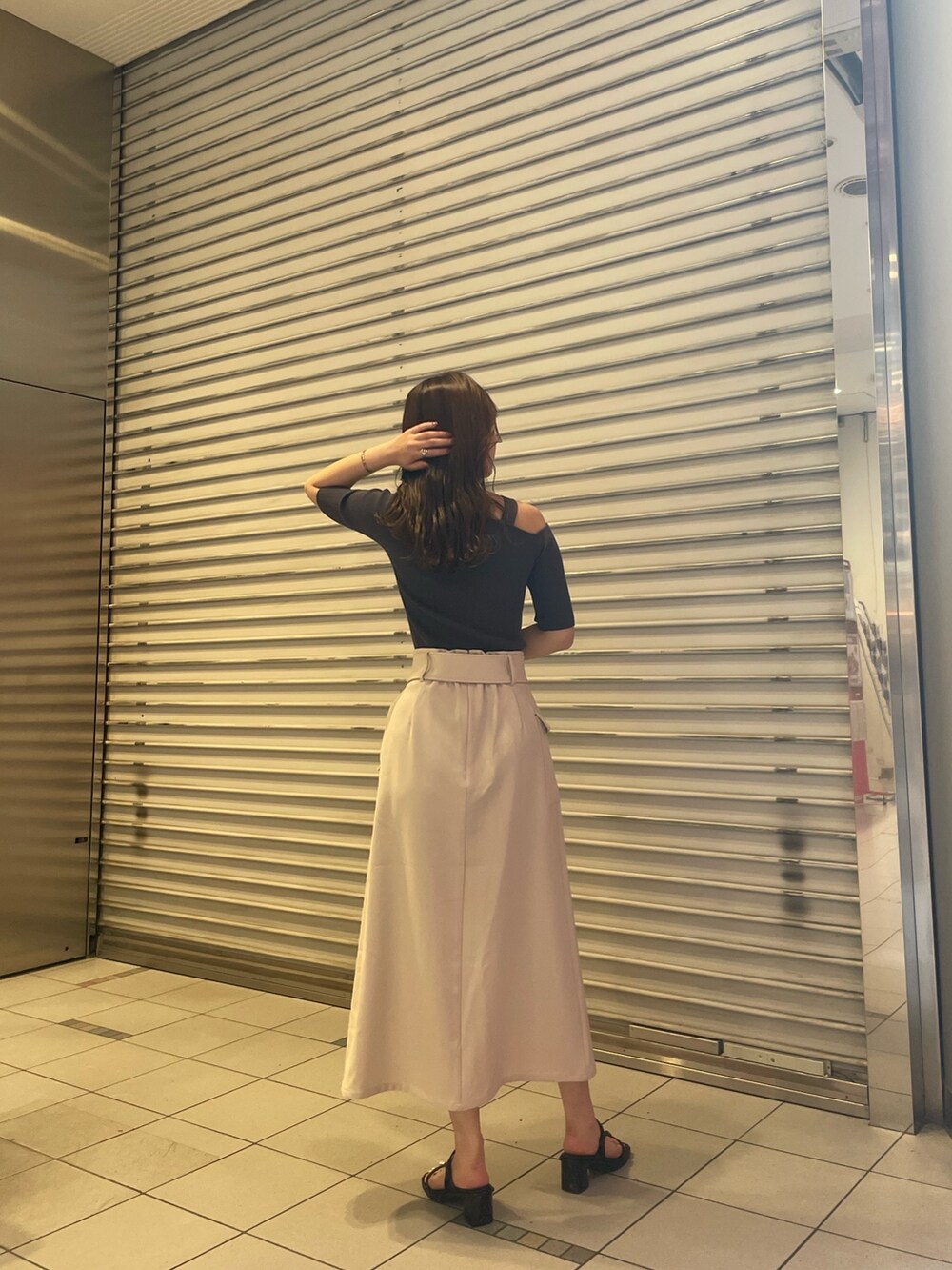 グレー系のニット/セーター、ホワイト系のスカート、ブラック系のサンダルを着用したレディースの春コーディネートの4枚目の写真