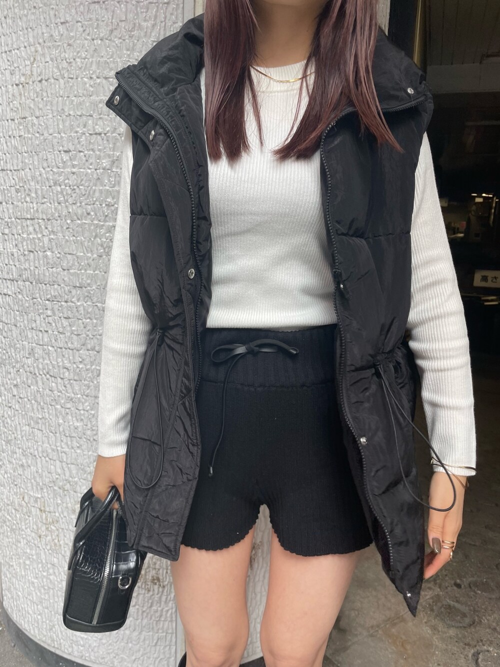 ブラック系のダウンベスト、ホワイト系のニット/セーター、ブラック系のその他パンツを着用したレディースの秋コーディネートの5枚目の写真