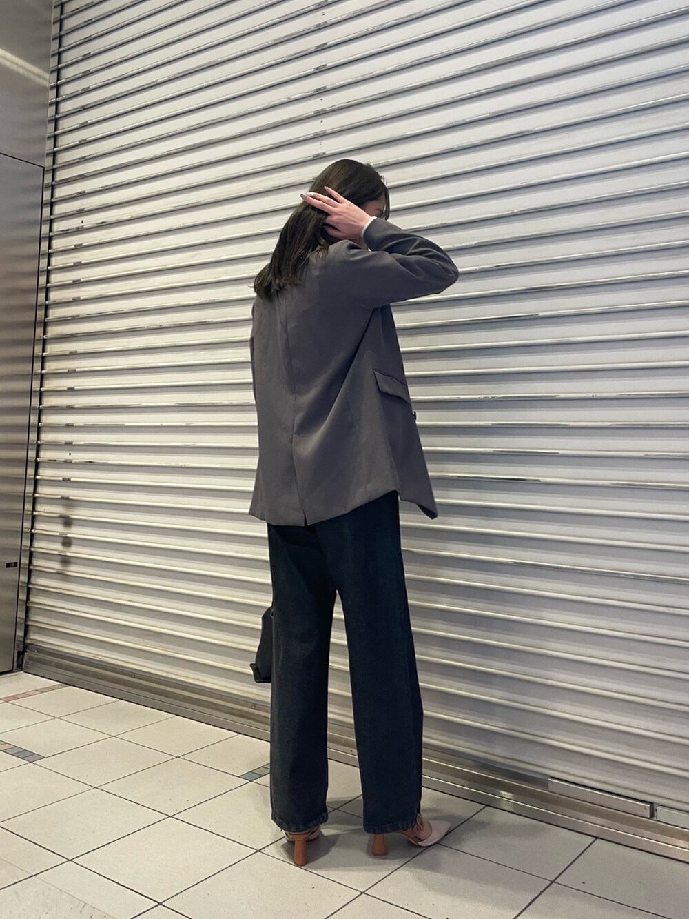 ブラック系のデニムパンツ、グレー系のテーラードジャケット、ホワイト系のニット/セーターを着用したレディースの冬コーディネートの2枚目の写真