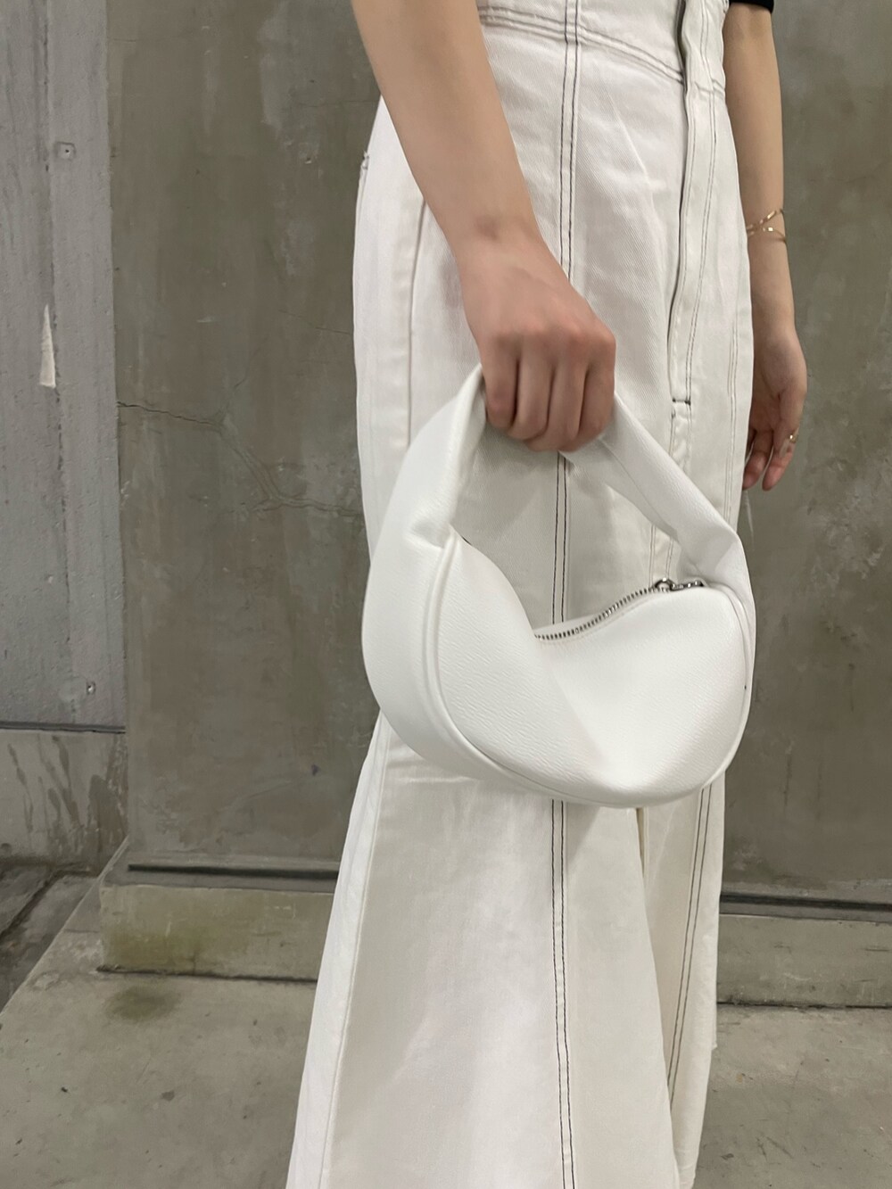 ブラック系のニット/セーター、ホワイト系のデニムスカート、ホワイト系のハンドバッグを着用したレディースの春コーディネートの7枚目の写真