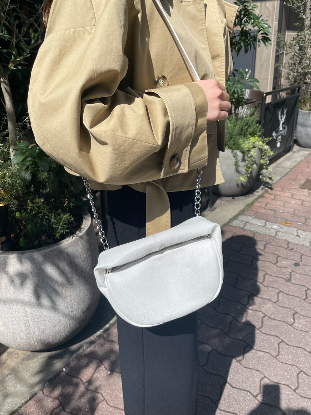 ホワイト系のハンドバッグ、ブラック系のブーツ、ブラック系のスカートを着用したレディースの春コーディネートの8枚目の写真