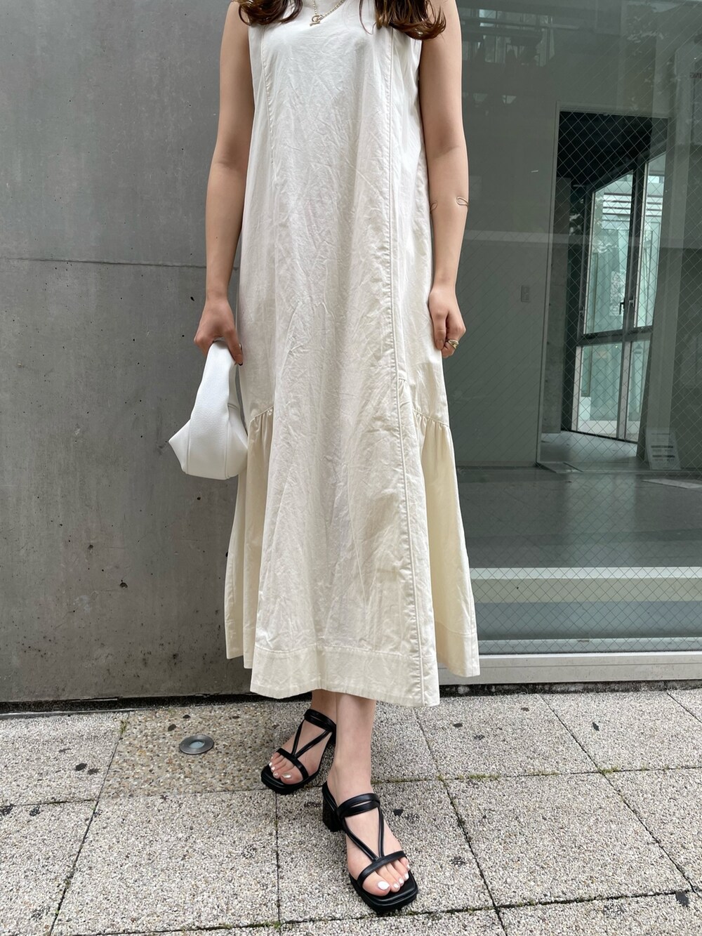 ホワイト系のワンピース、ホワイト系のハンドバッグ、ブラック系のサンダルを着用したレディースの夏コーディネートの5枚目の写真