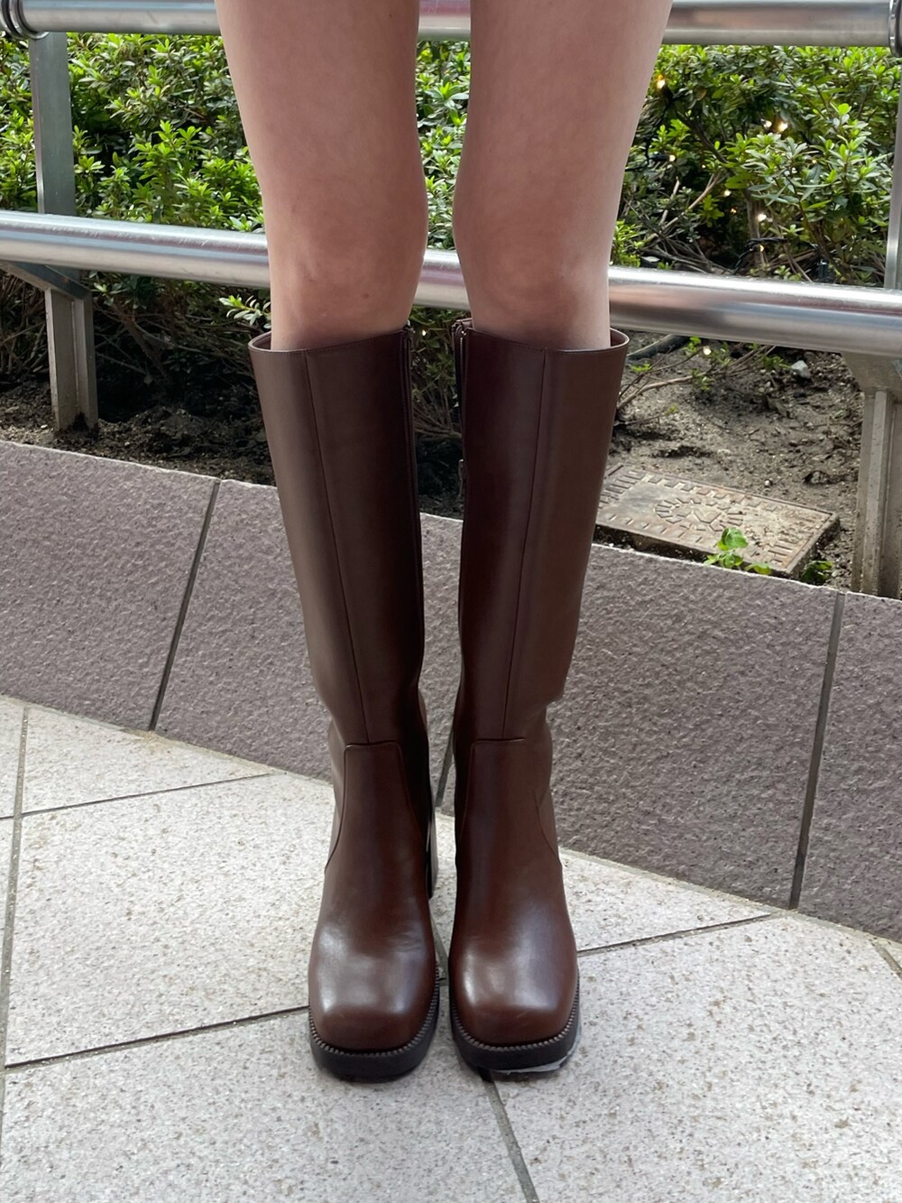 ホワイト系のニット/セーター、ブラウン系のスカート、ブラウン系のブーツを着用したレディースの秋コーディネートの7枚目の写真