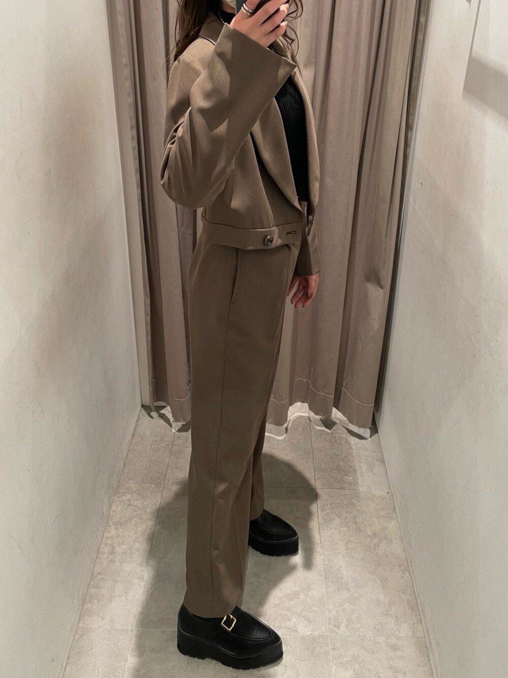 ブラウン系のテーラードジャケット、ブラック系のニット/セーター、シルバー系のハンドバッグを着用したレディースの春コーディネートの2枚目の写真