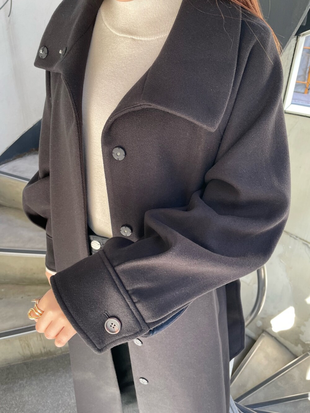 ブラック系のステンカラーコート、ホワイト系のニット/セーター、ブラック系のデニムパンツを着用したレディースの秋コーディネートの6枚目の写真