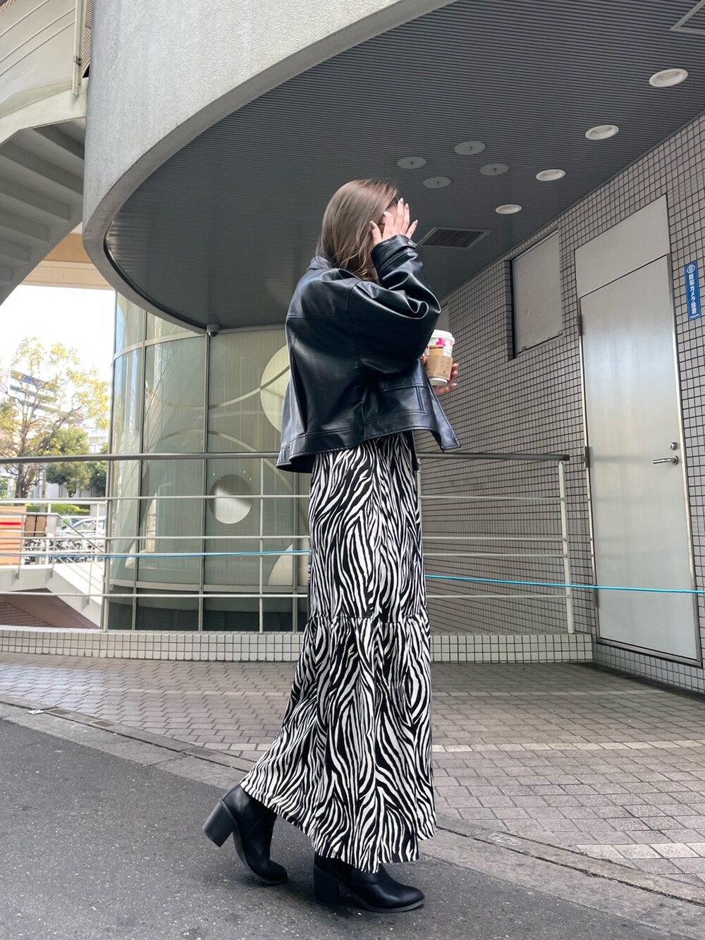 ブラック系のブルゾン、ホワイト系のスカート、ブラック系のニット/セーターを着用したレディースの春コーディネートの2枚目の写真