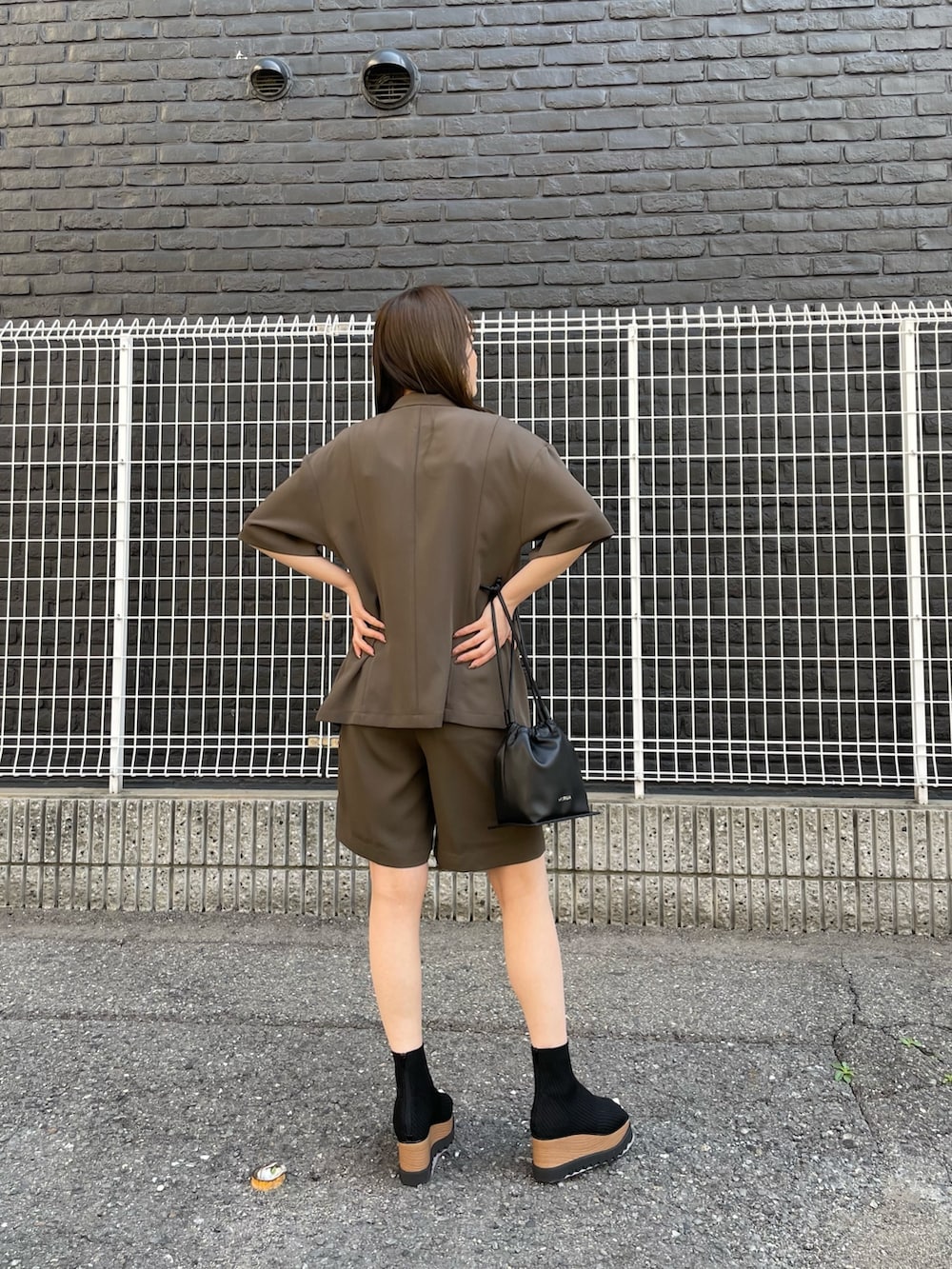 ブラウン系のテーラードジャケット、ホワイト系のタンクトップ、ブラウン系のスラックスを着用したレディースの春コーディネートの4枚目の写真